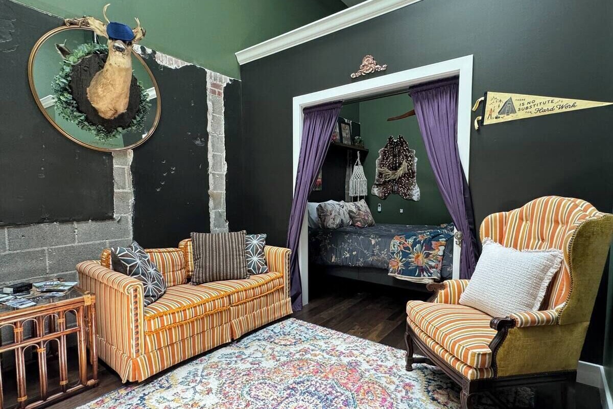 A cozy living room with a sofa, armchair, and a decorative mirror.