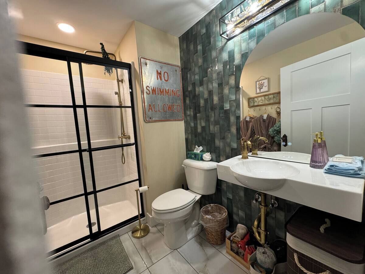 A bathroom with a shower, toilet, and sink. There is a sign that says "NO SWIMMING ALLOWED".