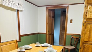 A dining area with a wooden table set for four, surrounded by wooden benches. - Cozy bungalow in downtown Zelie remote-work ready (Zelienople)
