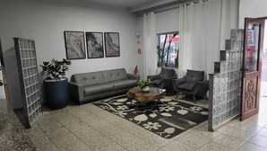 Un soggiorno moderno con un divano grigio, due poltrone, un tavolino da caffè e una grande pianta in vaso.