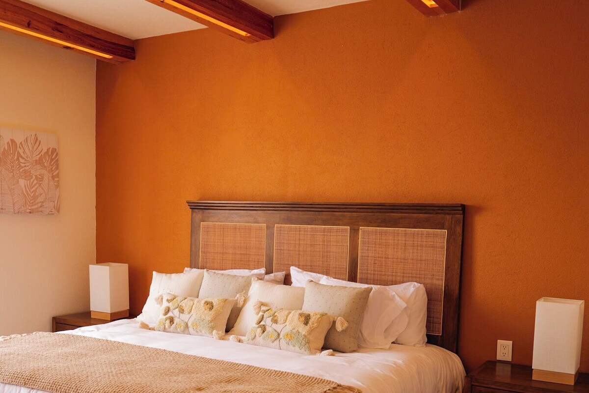 A bedroom with a large bed, wooden headboard, and a striped rug.