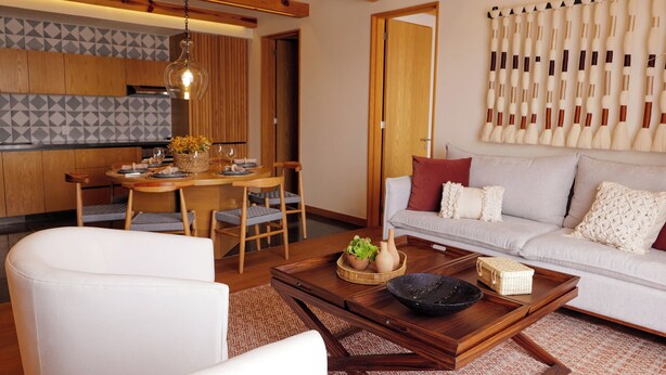 Uma sala de estar moderna com uma mesa de centro de madeira, um sofá e uma área de jantar com uma mesa e cadeiras de madeira.