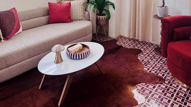 Una sala de estar con un sofá, una mesa de centro, una lámpara y una planta en maceta.