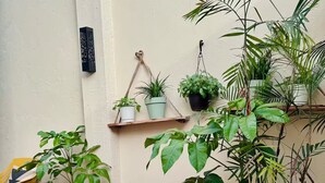 Un petit espace patio agrémenté de plantes en pot, d’une chaise en bois et d’un sol carrelé.