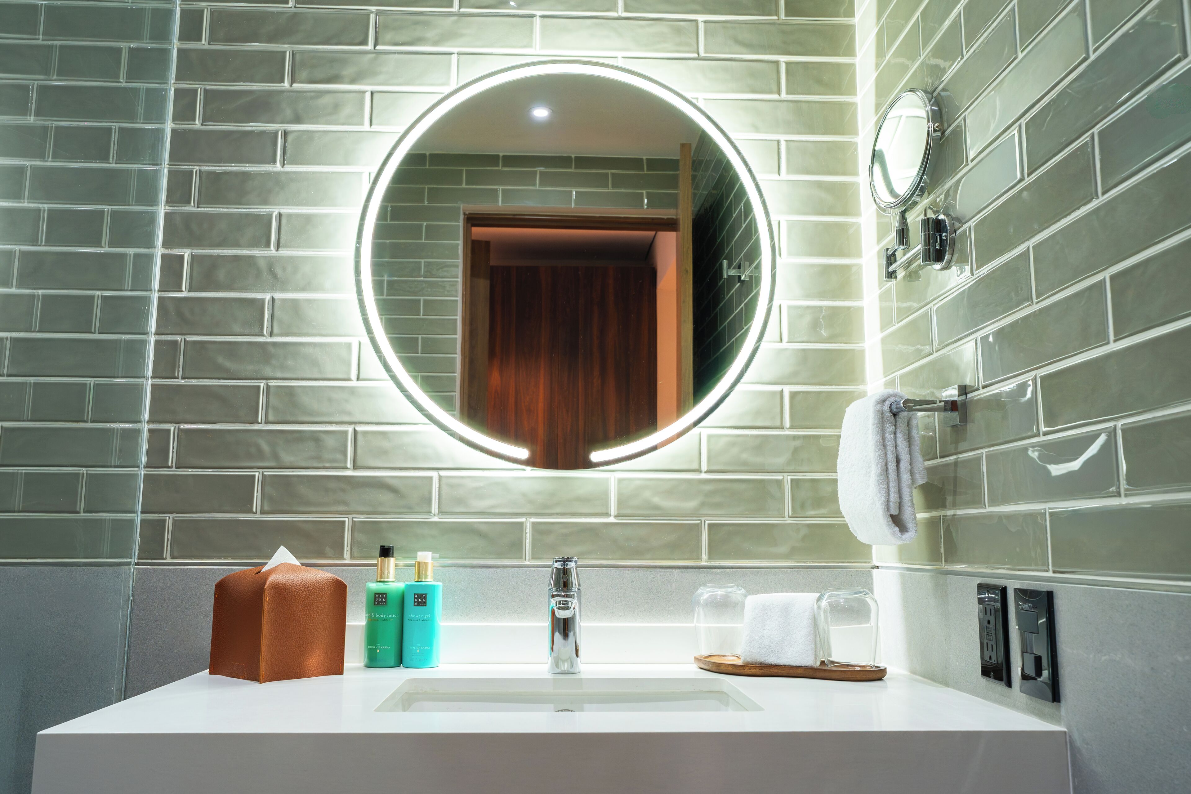 A bathroom with a white sink, a mirror with a circular frame, and a towel rack.