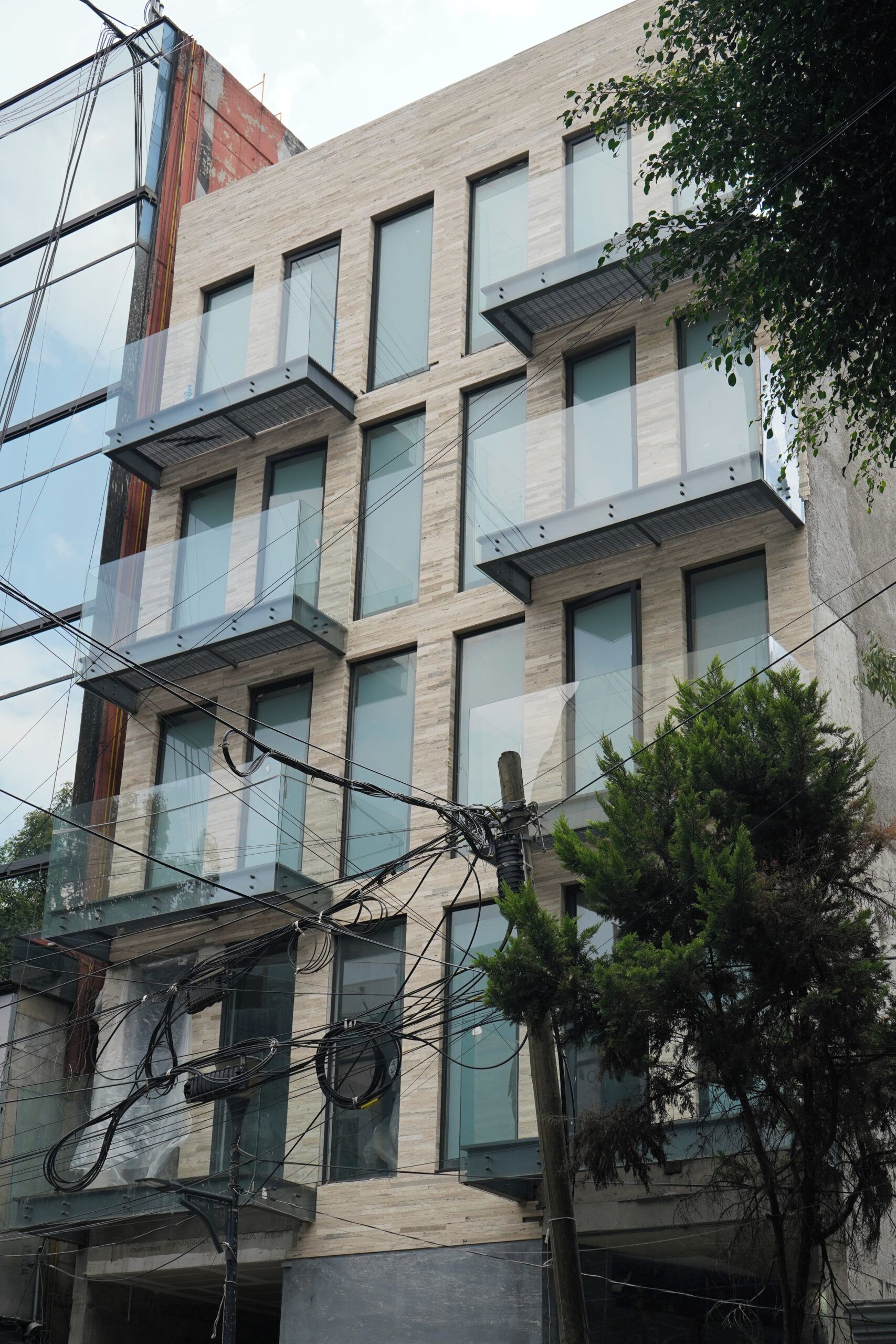 Monikerroksinen rakennus, jossa on moderni arkkitehtoninen ilme, ja siinä on parvekkeita sekä suuria ikkunoita.