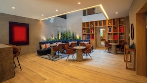 Un interior moderno con un conjunto de sofás, mesas redondas y una estantería de madera.