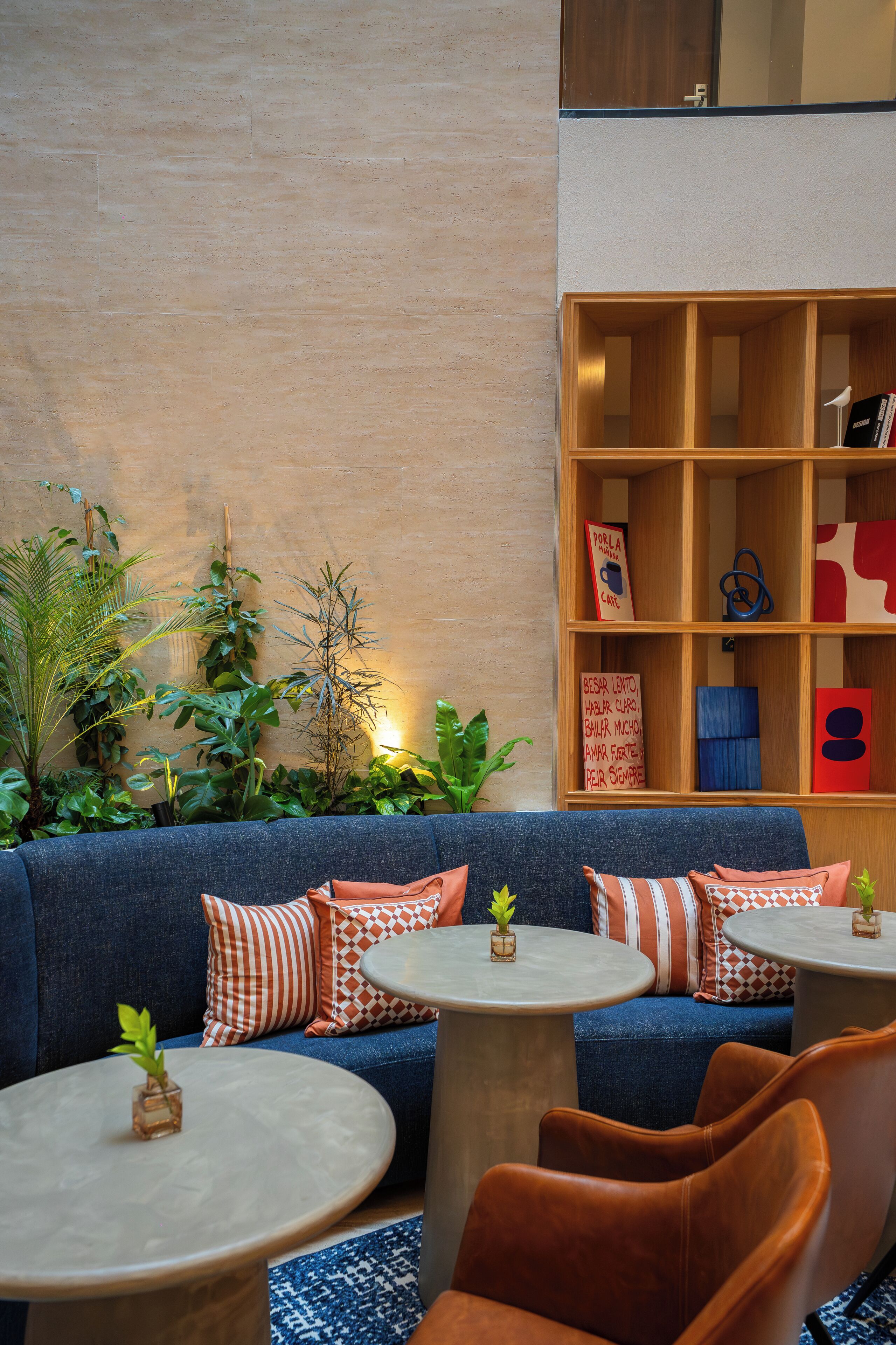 Eine Lounge mit einer Couch, zwei runden Tischen und einem Bücherregal.