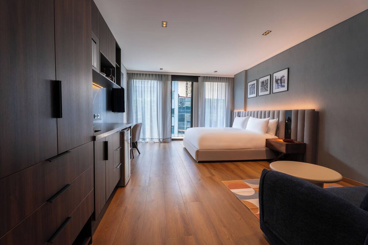 Una habitación de hotel moderna con cama, escritorio, silla, una mesita y televisor.