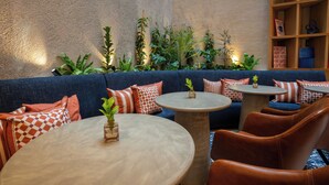Un espacio lounge acogedor con un sofá azul, mesas redondas y sillas de cuero.