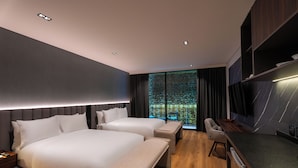 Una habitación de hotel moderna con dos camas, un escritorio y un televisor grande.