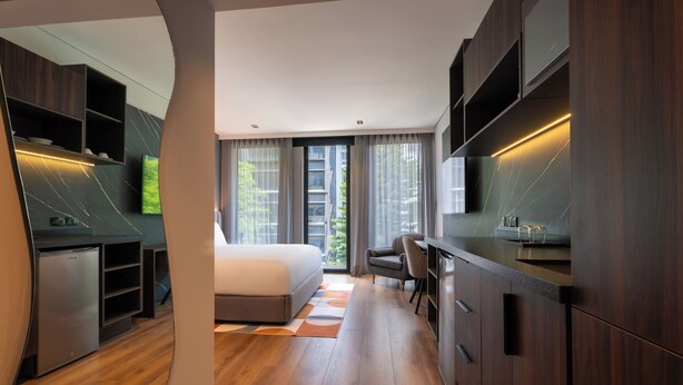 Un dormitorio moderno con cama, escritorio y televisor integrado.