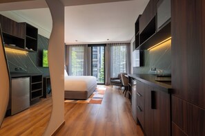 Un dormitorio moderno con cama, escritorio y televisor integrado.