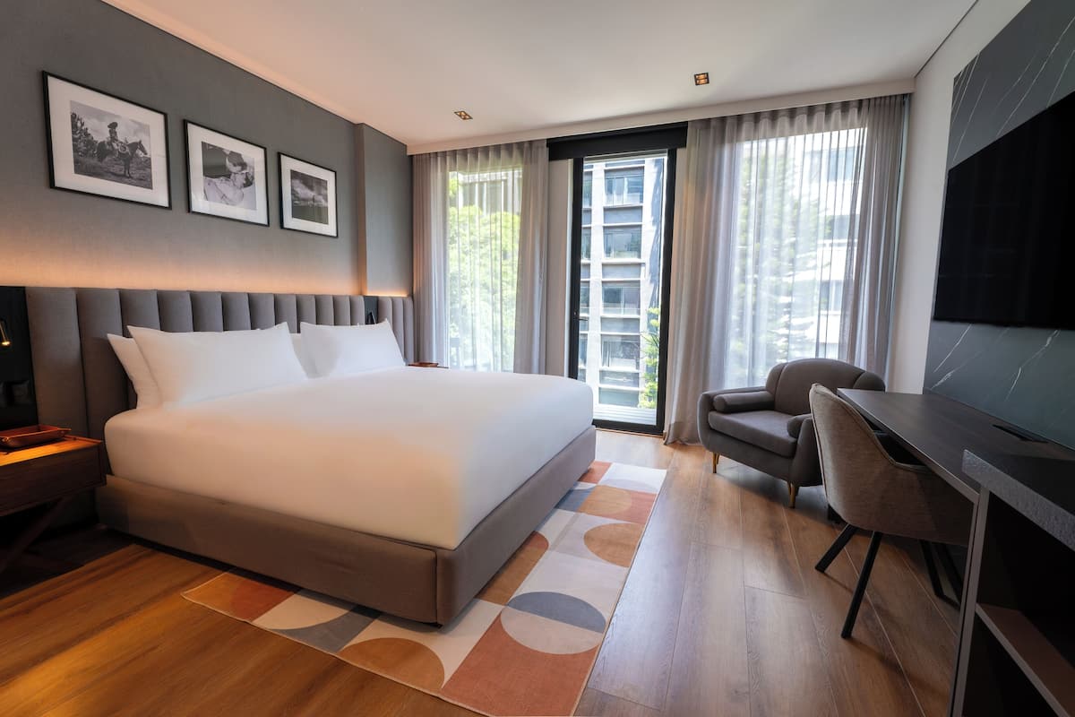 Una habitación de hotel moderna con una cama grande, un escritorio y un televisor.