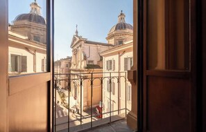 A view from a balcony with a wrought iron railing, overlooking a street with historic buildings and a dome structure. - PANORAMIC THREE-LEVEL PENTHOUSE WITH TERRACE BETWEEN COLOSSEUM & ROMAN FORUM (Roma)