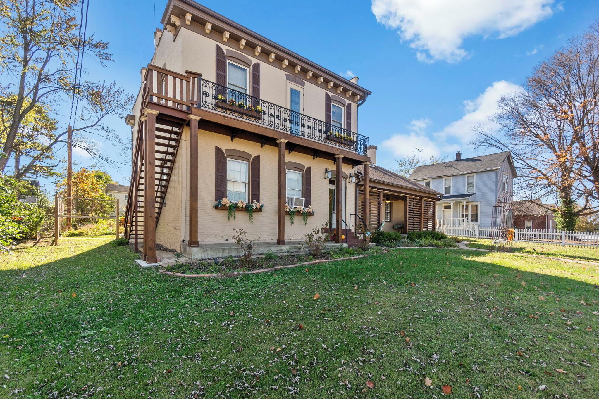 A two-story house with a balcony, a front porch, and a well-maintained lawn.