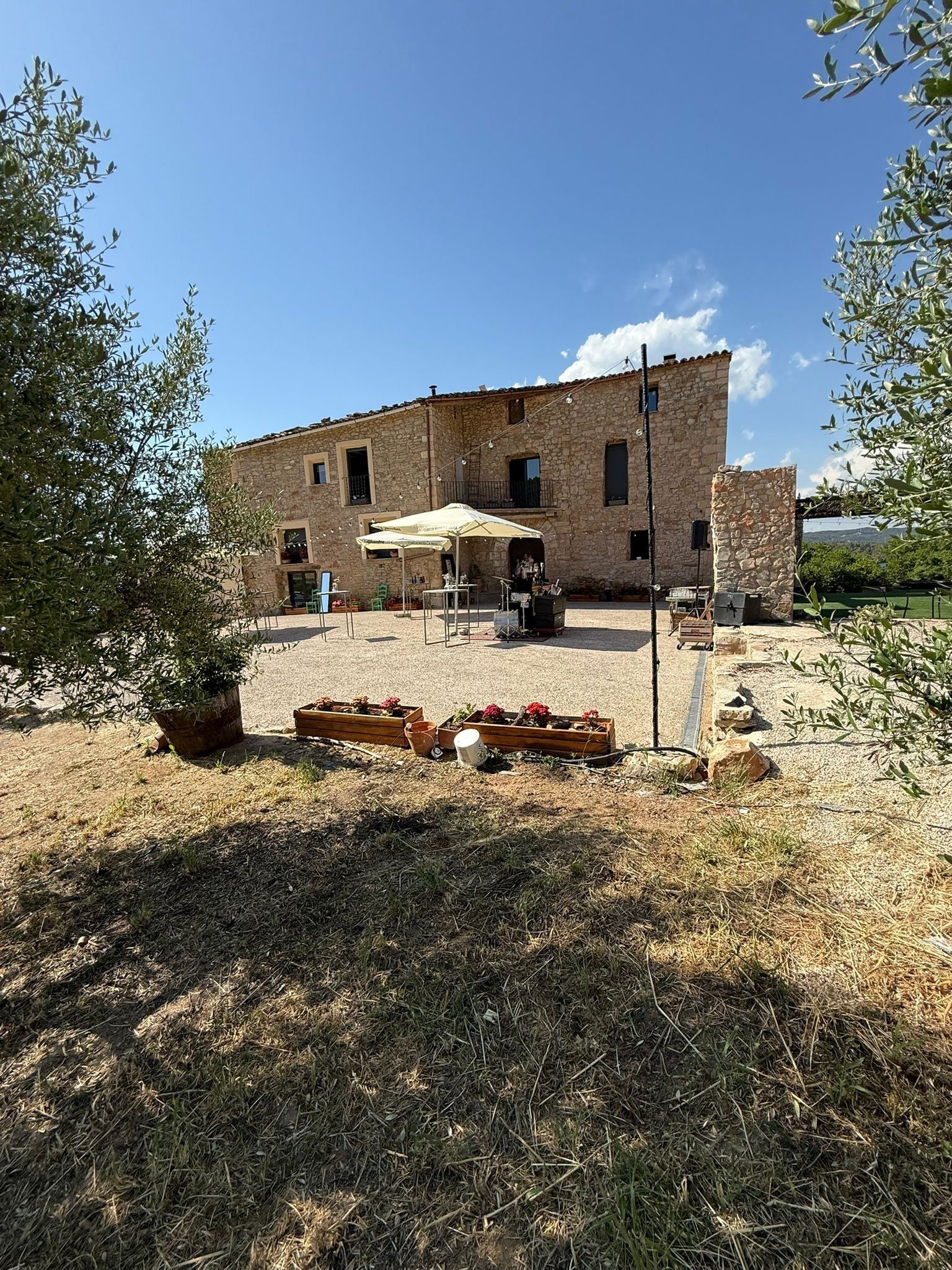 Un edificio de piedra con un patio que tiene asientos al aire libre y una mesa.