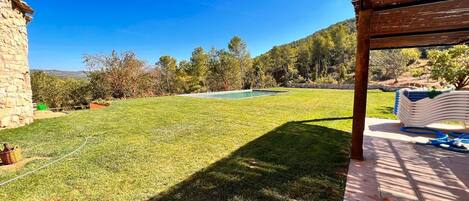 Un jardin avec une piscine, un mur en pierre et une pergola.
