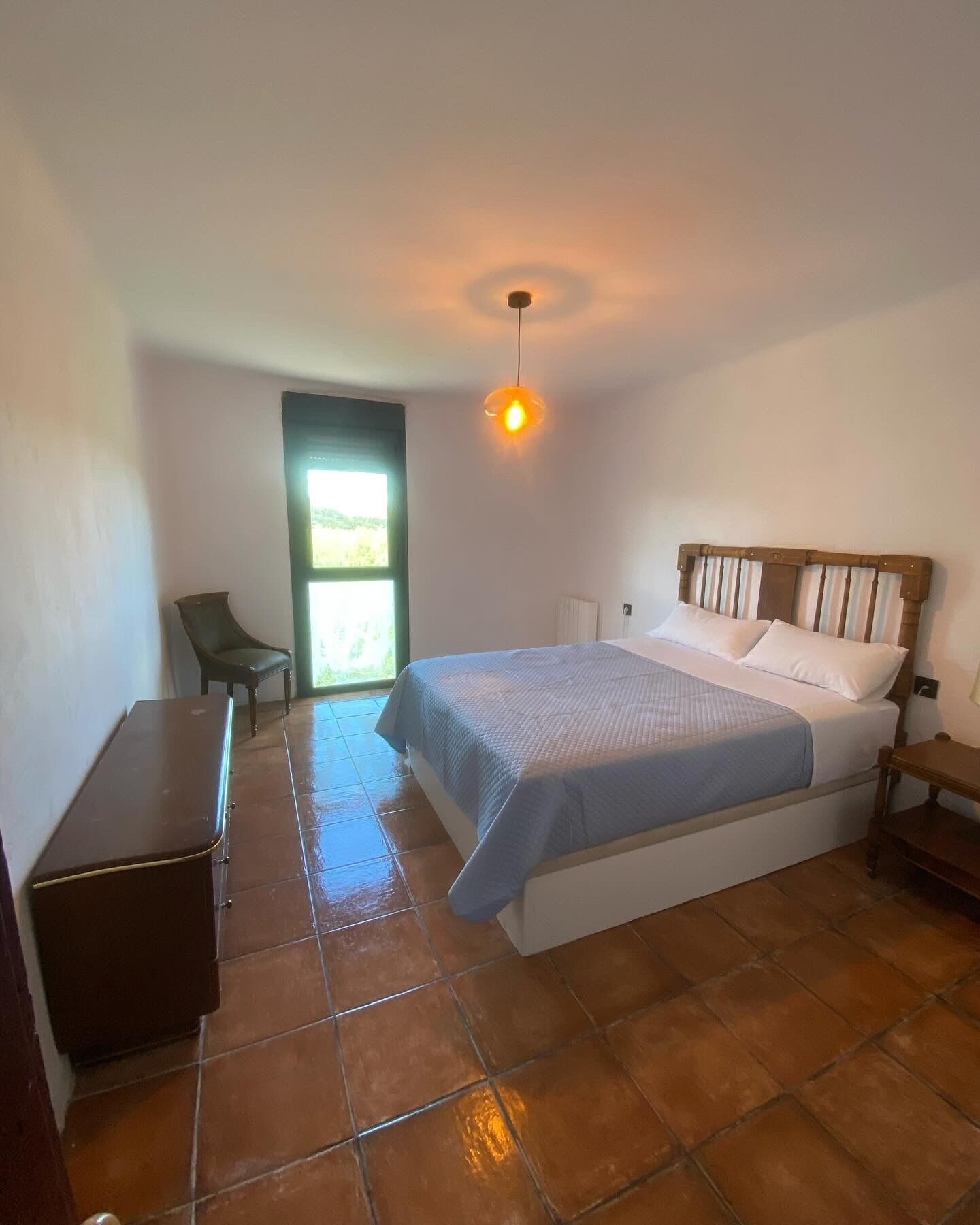 Un dormitorio con una cama, un escritorio, una silla y una ventana.