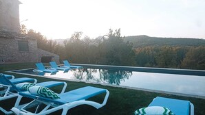 A poolside area with lounge chairs and a stone building in the background.