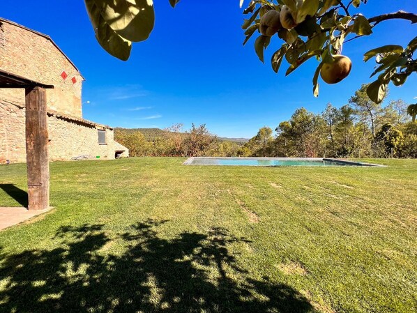 Un edificio de piedra con una piscina en un patio césped.