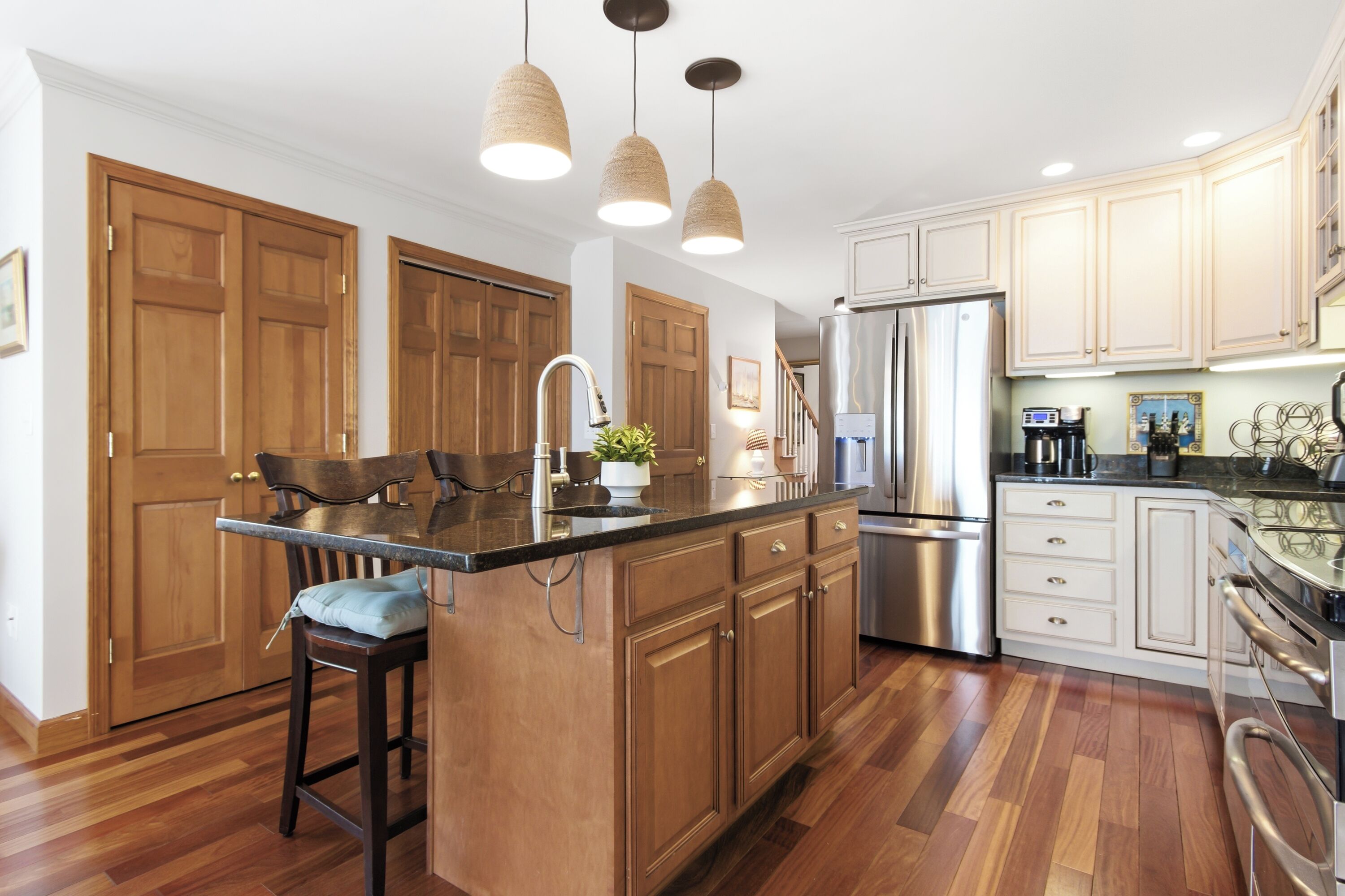 A kitchen with wooden cabinets, a stainless steel refrigerator, and pendant lights.