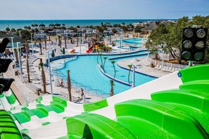 Um parque aquático com várias piscinas e toboáguas, cercado por casas de praia e vista para o oceano.