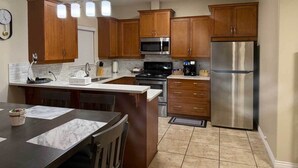 A modern kitchen with wooden cabinets, stainless steel appliances, and a marble countertop. - Osoyoos Lakeview Villa Canada's Warmest Paradise (Osoyoos)