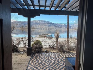 A covered outdoor area with a view of a lake and mountains.