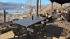 An outdoor patio with a table and chairs, a hanging chair, and a grill. - Osoyoos Lakeview Villa Canada's Warmest Paradise (Osoyoos)