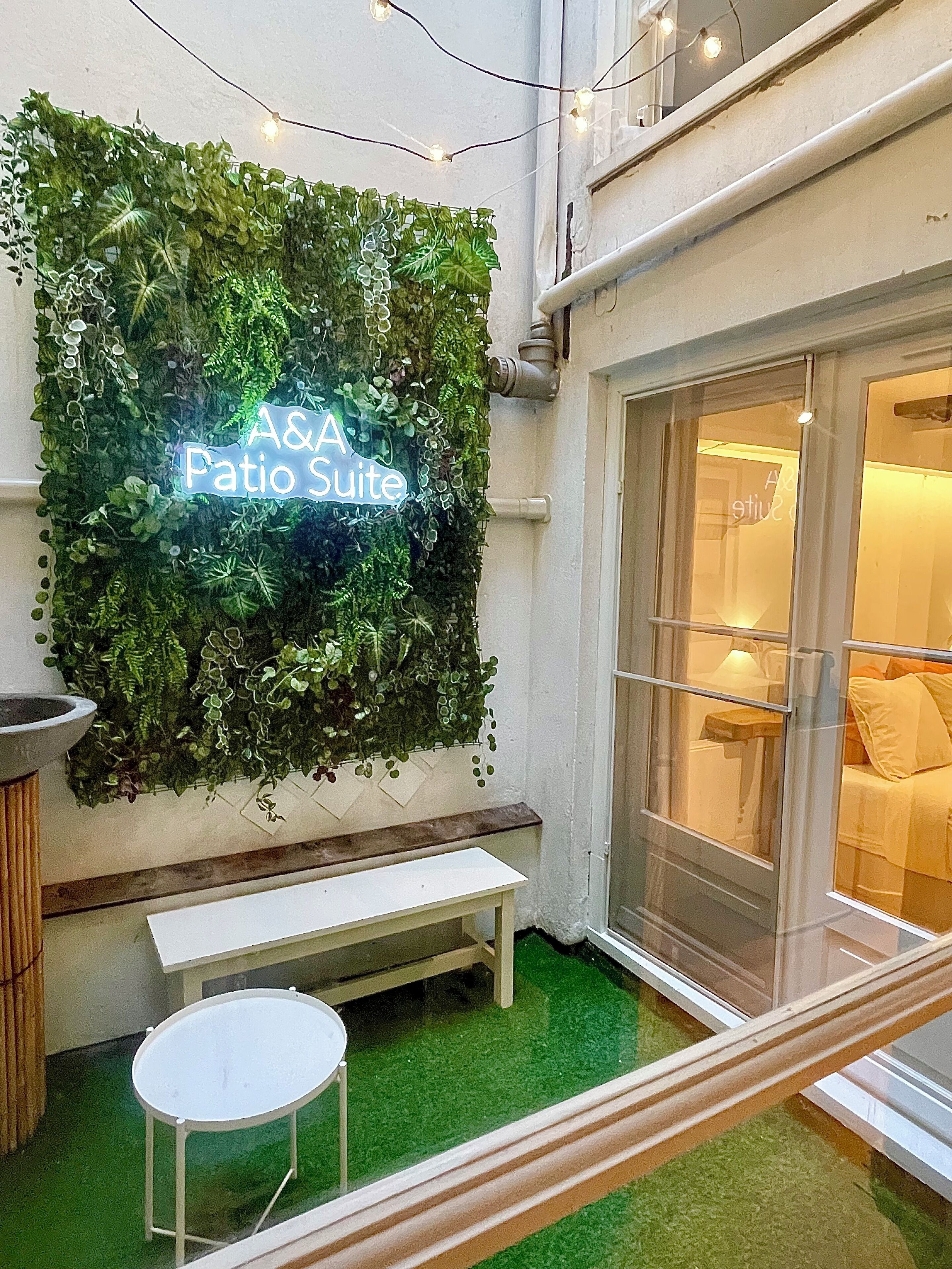 Een groene muur met een neonbord waarop staat 'A& A Patio Suite'.