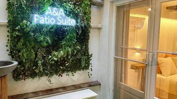 Een groene muur met een neonbord waarop staat 'A& A Patio Suite'.