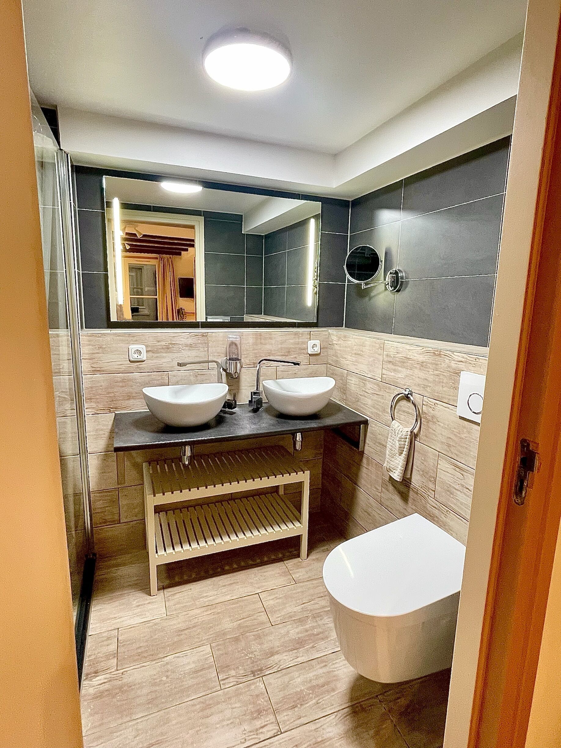 Een moderne badkamer met twee wastafels, een bad en een spiegel.