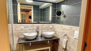 A modern bathroom with two sinks, a bathtub, and a mirror.