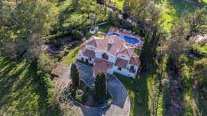 A large house with a swimming pool, surrounded by lush greenery and trees. - Casa Charador - Luxury Golf Villa (Alvor)