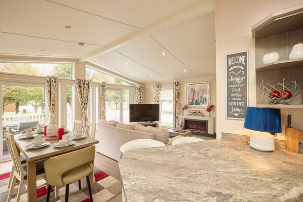 A modern living room with a fireplace, a television, and a dining area with a table set for four. - Host Stay Crucible Lodge (York)