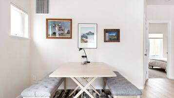 A dining area with a table, benches, and framed pictures on the wall.