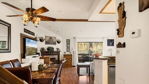 A spacious dining area with a wooden table and chairs, a fireplace, and a view of the outdoors. - Cozy 3BR Knotty Pine, Near Lake & Trails w Deck (Big Bear Lake)