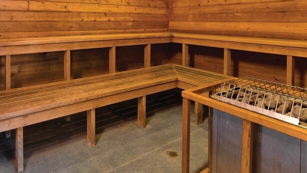 Una sauna con panche di legno e una panca in pietra.