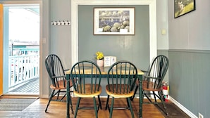 Un coin repas avec une table et des chaises, un tableau encadré au mur et une vue sur un bâtiment à l’extérieur.