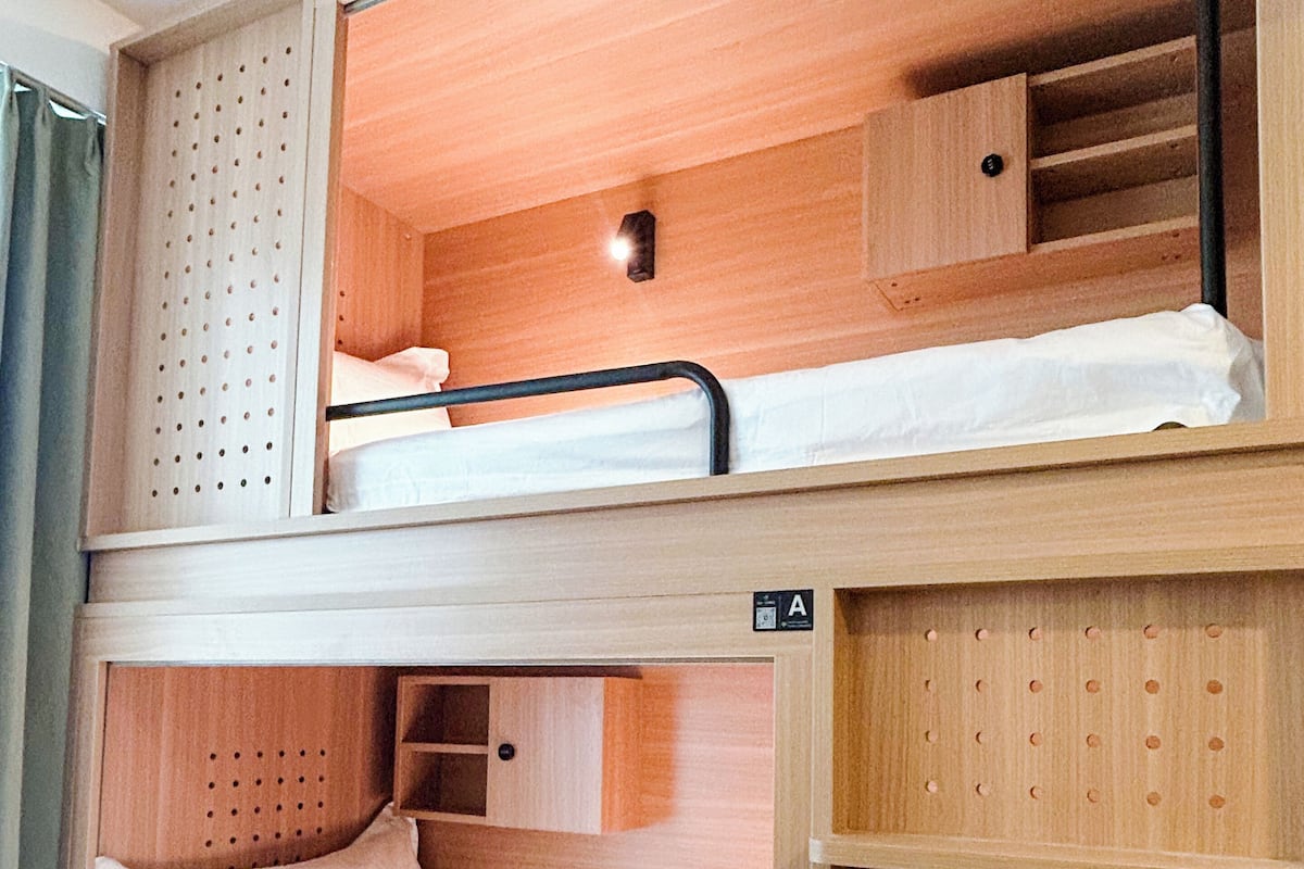 A bunk bed with a headboard, a shelf below, and a small cabinet.