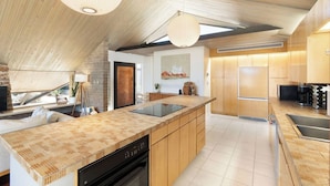 Une cuisine moderne dotée d’un grand îlot central, de meubles en bois et d’un plafond en pente.