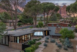 Ein modernes Haus mit flachem Dach, großen Fenstern und einem Garten mit verschiedenen Pflanzen.