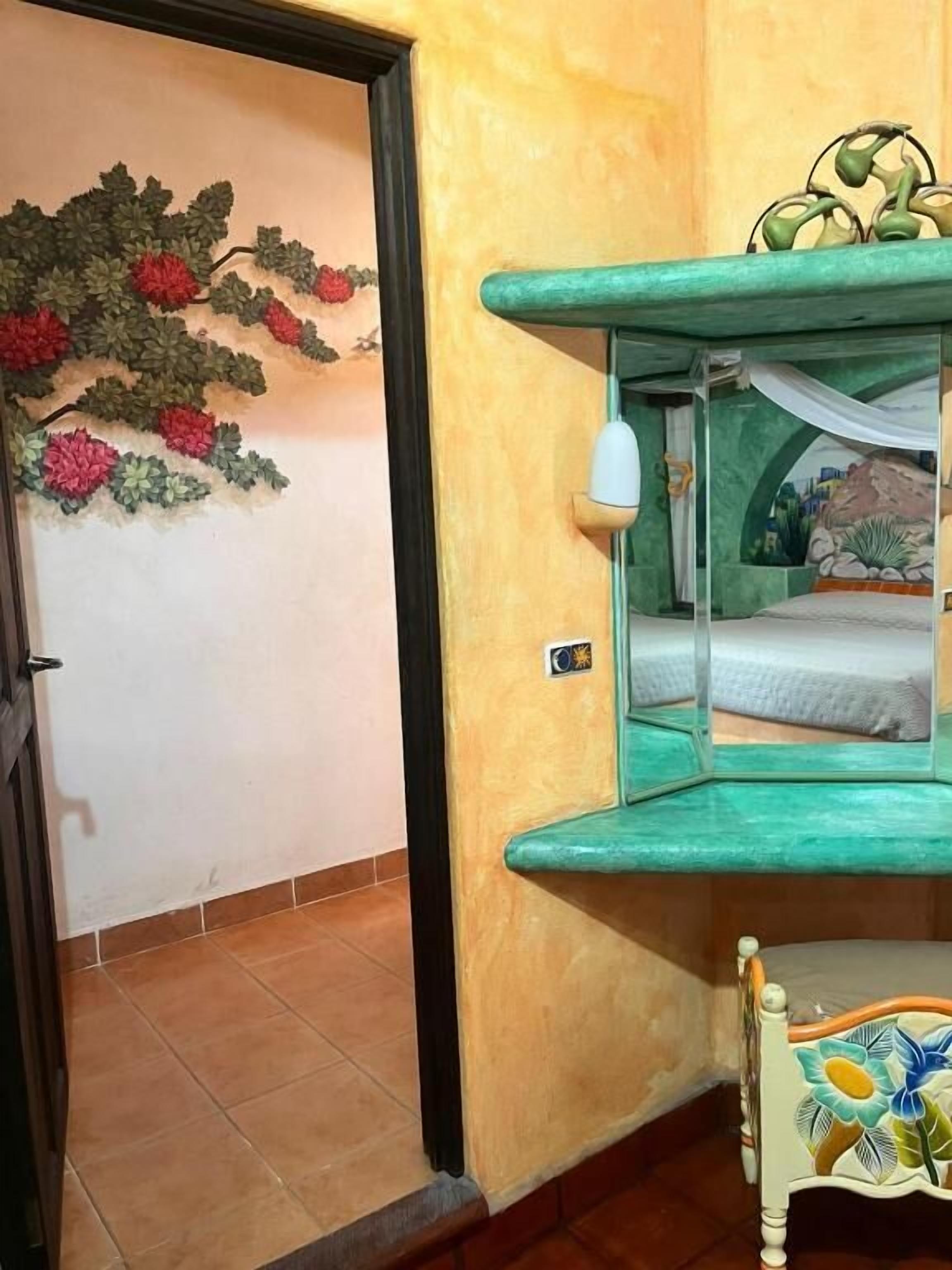 A room with a bed, a green wall, and a decorative wall hanging.