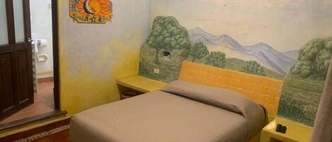 A bedroom with a bed, a nightstand, a wall mural, and a door.