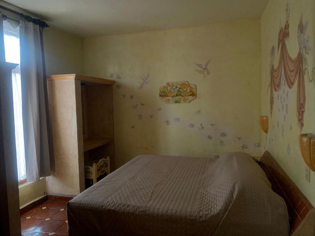 A bedroom with a bed, a wardrobe, and a window with curtains.