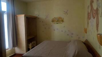 A bedroom with a bed, a wardrobe, and a window with curtains.