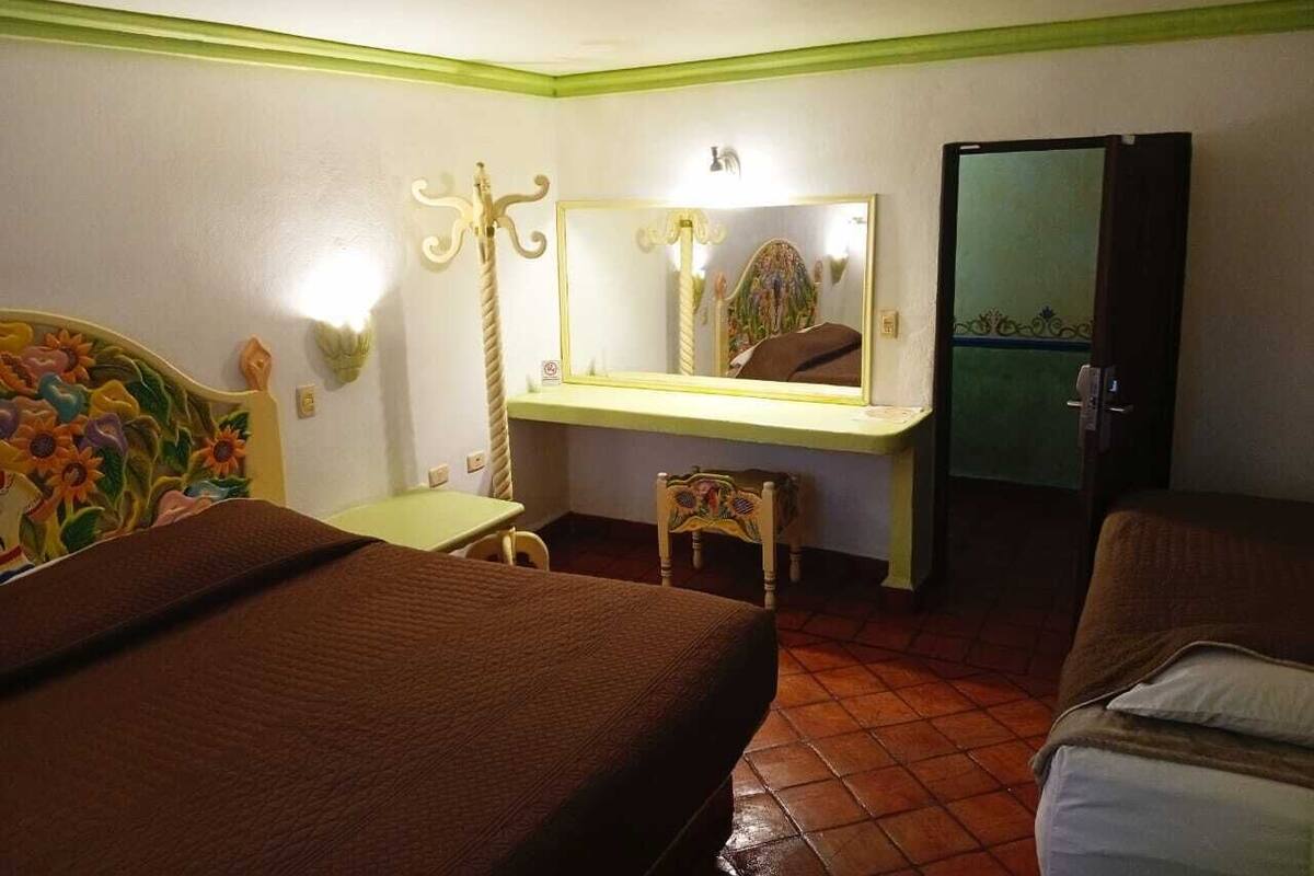 Une chambre d’hôtel comprenant un lit, un bureau avec un miroir, une chaise et une armoire.