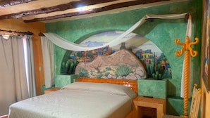A room with a bed, a chair, a mural on the wall, and a sword decoration.