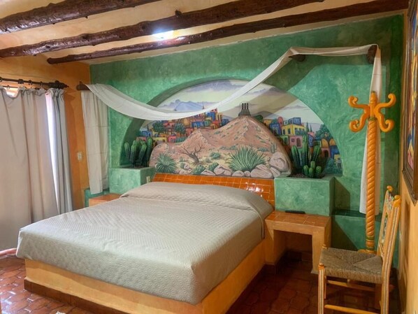 A room with a bed, a chair, a mural on the wall, and a sword decoration.